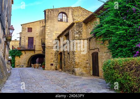 Mittelalterliche Steinhäuser mit grünen Reben bei Sonnenuntergang an einem Sommertag, Peratallada, Girona, Katalonien. Stockfoto