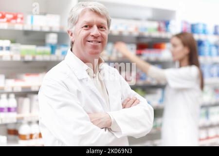 Apothekerin mit Assistentin. Porträt einer hübschen Apothekerin mit Assistentin im Hintergrund. Stockfoto