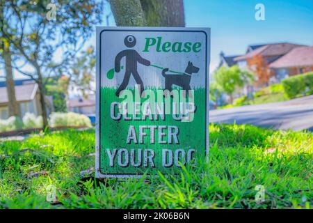 Bitte säubern Sie nach Ihrem Hundeschild in einem Viertel in San Francisco. Nahaufnahme eines Tieres Schilder gegen Baum, Straße, Häuser und blauen Himmel auf einem Su Stockfoto