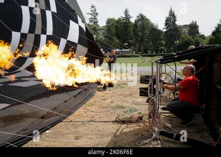 Bukarest, Rumänien - 27. August 2022: Ein Mann benutzt einen doppelten Gasbrenner, um einen Heißluftballon aufzublasen. Stockfoto