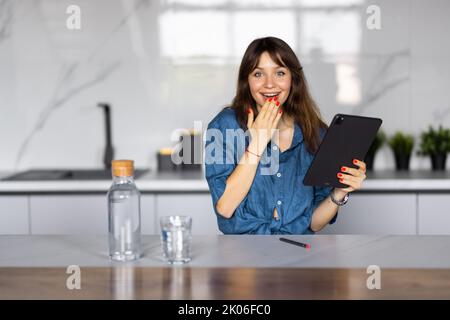 Schöne Frau erhielt einen Brief mit schlechten Nachrichten, Brünette liest eine Nachricht mit Trauer in der Küche zu Hause Stockfoto