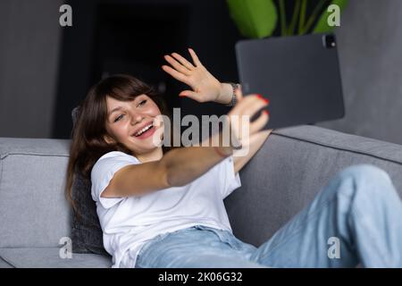 Technologie, Freizeit und Menschen Konzept - glücklich lächelnde Frau mit Tablet-pc-Computer mit Video-Chat und winken Hand zu Hause Stockfoto
