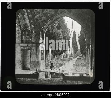 Reproduktion des Drucks, der Garden at Fin-nahe&#xaf;, Kashan, Iran zeigt. Mann, der unter dem Bogen sitzt, c1920. (Der 1590 fertiggestellte Fin-Garten ist der älteste erhaltene Garten im Iran). Stockfoto