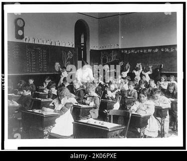 Kinder, die an Schreibtischen Ton modellieren und auf Tafel zeichnen, im Klassenzimmer von Washington, D.C., (1899?). Stockfoto