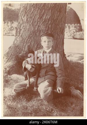 Kermit Roosevelt und Jack, der Hund, 1902. Das Foto zeigt Kermit Roosevelt, der seinen Hund hält und unter einem Baum sitzt. [Sohn von Präsident Theodore und Edith Roosevelt]. Stockfoto