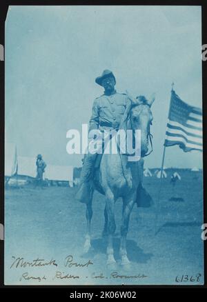 Montauk Point, Rough Riders, Col. Roosevelt, 1898. Das Foto zeigt Theodore Roosevelt in Rough Rider Uniform, auf einem Pferd sitzend, nach vorne gerichtet, mit amerikanischer Flagge auf der rechten Seite. Stockfoto