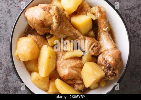 Semur Ayam Chicken Eintopf in süßer Sojasoße mit Kartoffeln auf einem weißen Teller in der Nähe auf dem Tisch serviert. Horizontale Draufsicht von oben Stockfoto