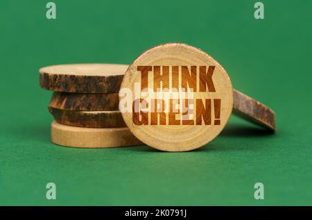 Ökologisches Konzept. Auf einer grünen Oberfläche, hölzerne Kreise auf einer Inschrift - Think Green Stockfoto