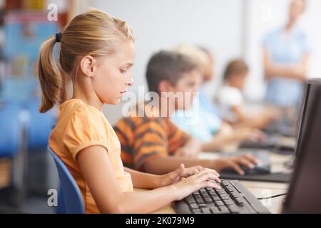 Fleißig an den Computern arbeiten. Eine Gruppe von kleinen Kindern, die hart im Computerunterricht arbeiten. Stockfoto