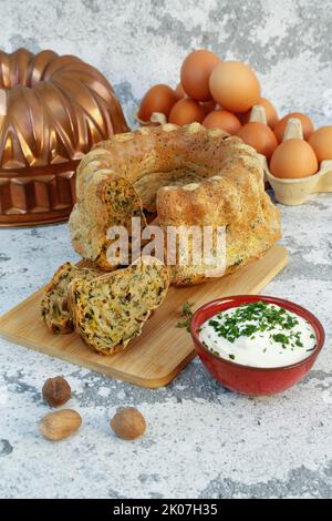 Schwäbische Küche, Mangold-Gugelhupf mit Kräuterdip, Hüttenkäse, herzhaftes Gebäck auf Holzbrett, herzhafter Kuchen, vegetarisch, backen, Muskatnuss davor, Eier Stockfoto