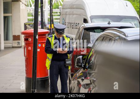 LONDON - 21. Mai 2022: Der Verkehrsleiter nutzt neben der traditionellen roten britischen Post Box das Smartphone Stockfoto