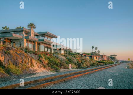 Häuser in Del Mar Südkalifornien entlang der Eisenbahn am Strand bei Sonnenuntergang. Fassade von gehobenen Häusern am Meer mit Blick auf die Küste, blauen Himmel, Eisenbahn, Stockfoto