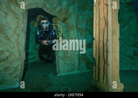 Der Taucher taucht durch das kleine Tor der stilisierten Ruine des antiken Tempels in 20 Metern Tiefe im Indoor-Tauchturm, Indoor Dive Center Dive4Life, Siegburg Stockfoto