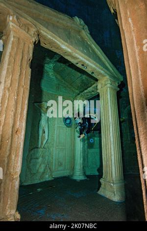 Taucher taucht durch stilisierte Ruine des Portaleingangs des alten Tempels in 20 Metern Wassertiefe im Indoor-Tauchturm, im Vordergrund nachgebildet Stockfoto