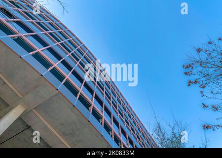 Blick nach oben auf das Äußere eines Parkhauses in einem Gebäude gegen den blauen Himmel. Ein mehrstufiger überdachter Parkplatz für Bewohner von Wohnungen oder Kondomen Stockfoto