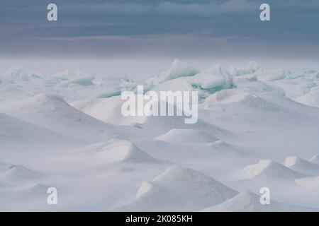 Der Wind bläst Schnee auf der Oberfläche der Green Bay, Lake Michigan Eis schiebt die scharfen Kanten des Eises zu mildern und eine andere Welt zu schaffen Stockfoto