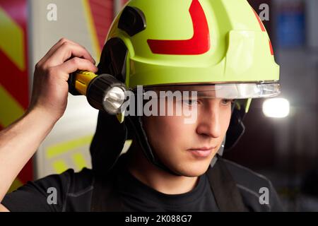 Junger Feuerwehrmann in Uniform, der vor einem Feuerwehrauto steht Stockfoto