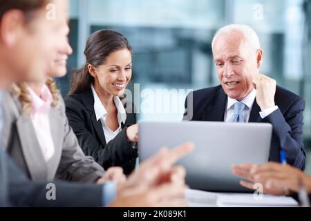 Erläuterung des Geschäftsplans im Detail. Attraktive Geschäftsfrau, die während eines Meetings ihrem Senior etwas auf einem Laptop vorführt. Stockfoto