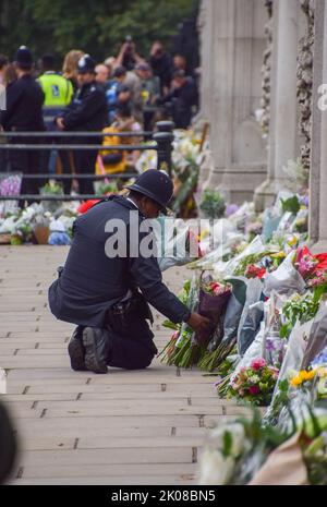 London, Großbritannien. 9.. September 2022. Ein Polizeibeamter legt Blumen für einen Trauernden in einem für die Öffentlichkeit unzugänglichen Gebiet außerhalb des Buckingham Palace, als Königin Elizabeth II. Im Alter von 96 Jahren stirbt. Stockfoto