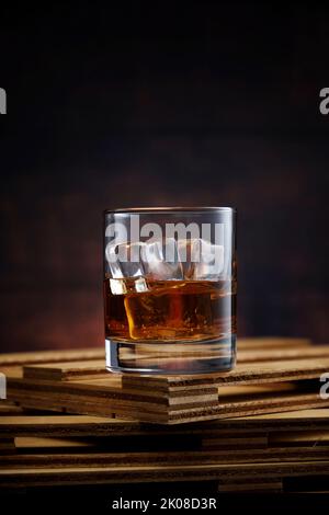 Kristallglas mit Whiskey und Eis auf Holztisch Stockfoto