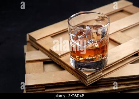 Kristallglas mit Whiskey und Eis auf Holztisch Stockfoto