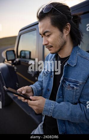 Glücklicher chinesischer Mann mit mittlerem Erwachsenen und Smartphone Stockfoto