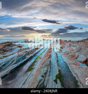 Dämmerung Ozeanküste mit gerippten stratiforme Felsformationen. (Atlantik, Spanien). Stockfoto