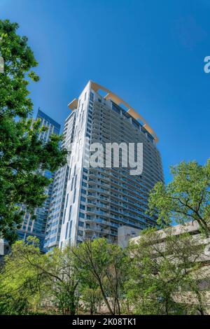 Außenansicht einer hoch aufragenden Wohnanlage oder Wohnung in Austin Texas vor blauem Himmel. Modernes Wohngebäude im Wohngebiet der Innenstadt mit üppigen Bäumen Stockfoto