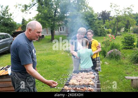 Mann kocht Schweinefleisch Kebabs auf Spieße im Hinterhof Stockfoto