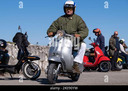 Silver Lambretta Li 150 Special, klassischer italienischer Vintage-Roller, der von einem Mann in grünem Parka gefahren wird. Ballintoy, Großbritannien - 10. September 2022. Stockfoto