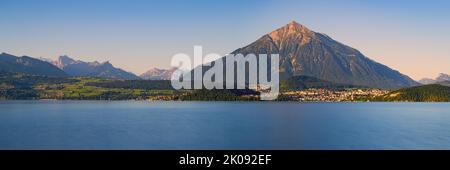 Ein breites Panoramabild von einem schönen Sommermorgen am Thunersee. Der Berg Niesen (2363 Meter hoch) ragt weit über die Landschaft, aber der Platz Stockfoto