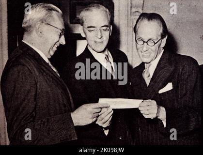 Das dritte Geschenk aus Australien in drei Jahren. Sir Stafford Cripps erhält einen Scheck von Herrn Mighell. Sir Richard Stafford Cripps CH QC FRS (24. April 1889 - 21. April 1952) war ein Politiker, Rechtsanwalt und Diplomat der britischen Labour Party. Sir Norman Rupert Mighell CMG (12. Juni 1894 - 13. April 1955) war ein australischer ANZAC-Offizier, Überlebender von Gallipoli, Unternehmensdirektor, Beamter und Diplomat. Nach seinem Militärdienst leitete Mighell viele Unternehmen und diente später Australien als stellvertretender Hochkommissar für Australien in London. Stockfoto