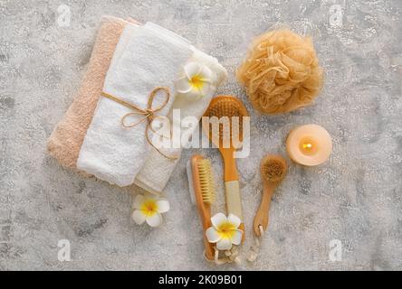 Badeset mit tropischen Blumen und brennender Kerze auf hellem Hintergrund Stockfoto