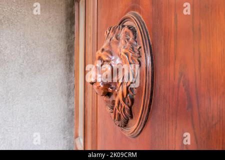 Löwenkopf aus Holz an der Vordertür. Seitenansicht, Nahaufnahme. Stockfoto