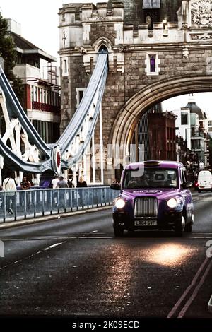 An einem sonnigen Sommerabend im Zentrum Londons fährt ein Taxi der Londoner Black über die Tower Bridge. Das Auto befördert Passagiere in ganz London. Stockfoto