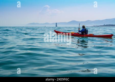 Seekajakfahren in der Nähe des Trwyn Du Lighthouse, auch bekannt als Penmon Lighthouse vor Puffin Island an der Küste von Anglesey, Wales, Großbritannien Stockfoto