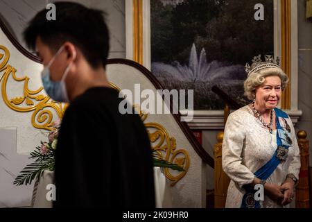 Ein Mann geht an einer Wachsfigur der verstorbenen britischen Königin Elizabeth II. Im Wuhan Madame Tussauds Wachsmuseum vorbei. Königin Elizabeth II., die dienstälteste Monarchin der britischen Geschichte und eine Ikone, die Milliarden von Menschen auf der ganzen Welt sofort zu erkennen ist, starb am 8. September im Alter von 96 Jahren auf ihrem schottischen Hochland-Retreat. Stockfoto