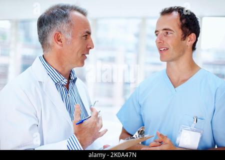 Arzt und Resident diskutieren Optionen. Zwei Männer im Gesundheitsberuf diskutieren. Stockfoto