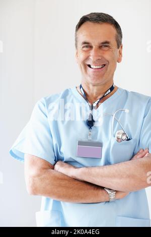 Selbstbewusster Arzt mit gefalteten Händen gegen Weiß. Porträt eines selbstbewussten Arztes mit gefalteten Händen vor weißem Hintergrund. Stockfoto
