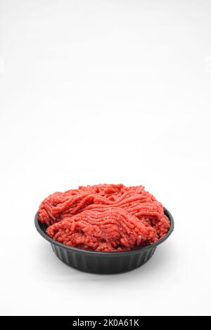 Frisches rohes Hackfleisch in der schwarzen Schüssel auf weißem Hintergrund Stockfoto
