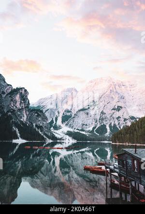 Atemberaubende Aussicht auf den Pragser See (Lago di Prags) mit einigen Holzbooten und wunderschönen Bergen, die sich im Wasser spiegeln. Stockfoto