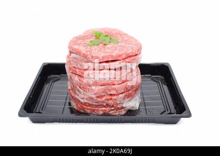 Stapel frisches rohes Rindfleisch Burger Patties in schwarzem Tablett isoliert auf weißem Hintergrund Stockfoto
