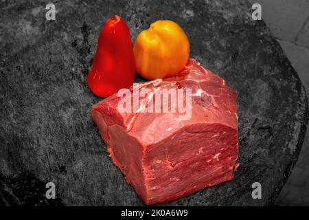 Rohes Rindfleisch-Steak mit frischen Paprika auf dunkler rustikaler Oberfläche Stockfoto