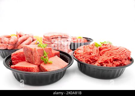 Seitenansicht von verschiedenen rohen Rindfleischschnitten, Hackfleisch, Würstchen und Burger Patties isoliert auf weißem Hintergrund Stockfoto