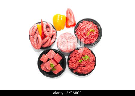 Top-Ansicht von ausgewählten rohen Rindfleischprodukten Würstchen, Hackfleisch, Burger Patty, Beef Cubes und Streifen isoliert auf weißem Hintergrund Stockfoto