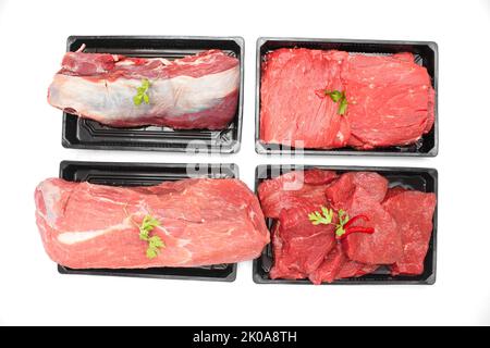 Ansicht von oben auf verschiedenen rohen Rindfleisch Steaks und Schenkeln in schwarzen Tabletts isoliert auf weißem Hintergrund Stockfoto