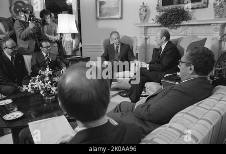 Präsident Gerald Ford (Mitte) sitzt auf einem Stuhl vor dem Kamin, mit dem israelischen Premierminister Yitzhak Rabin (links) und anderen, darunter US-Außenminister Henry Kissinger (rechts), im Weißen Haus. 1976 Stockfoto