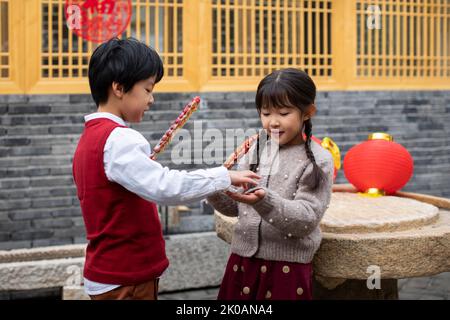 Glückliche chinesische Geschwister essen kandierte Hagebutten Stockfoto