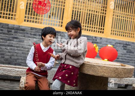 Glückliche chinesische Geschwister essen kandierte Hagebutten Stockfoto