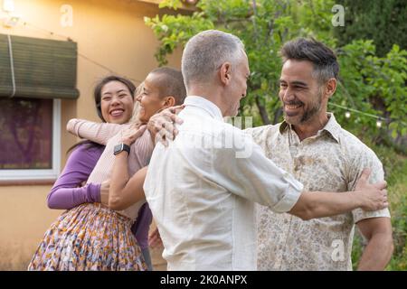 Multiethnische Männer und Frauen mittleren Alters grüßen einander und huddeln sich glücklich zusammen. Stockfoto